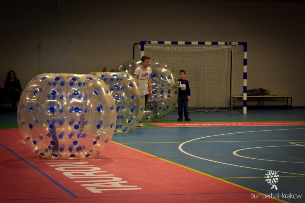 Children playing bumper ball in a school gym