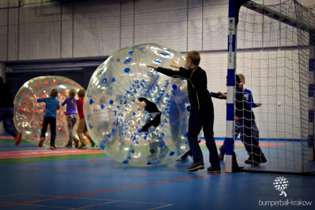 Children playing bumper ball in a school gym