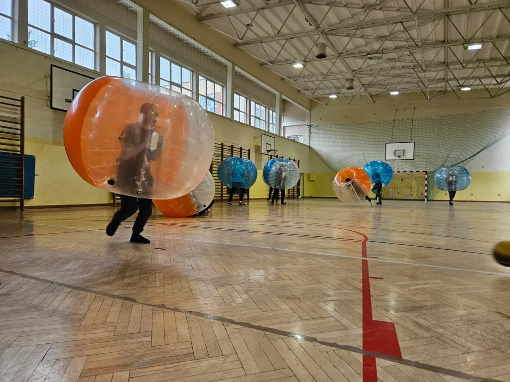 Teams in orange and blue bumper balls in a sports hall