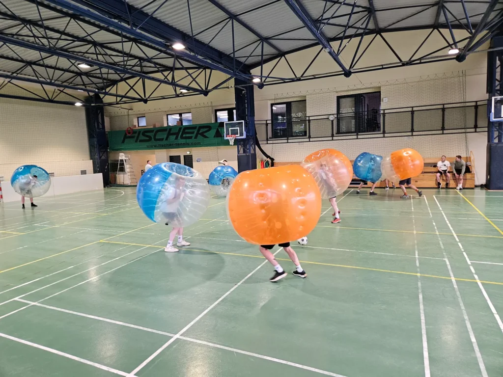 Teams in orange and blue bumper balls in a sports hall