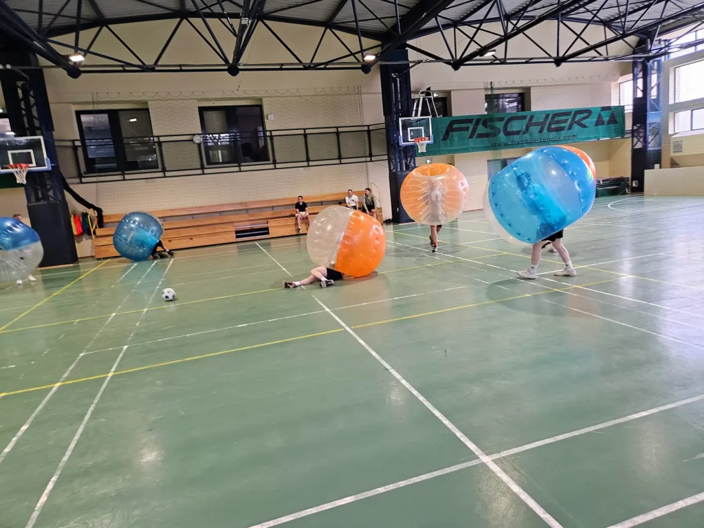 Teams in orange and blue bumper balls in a sports hall