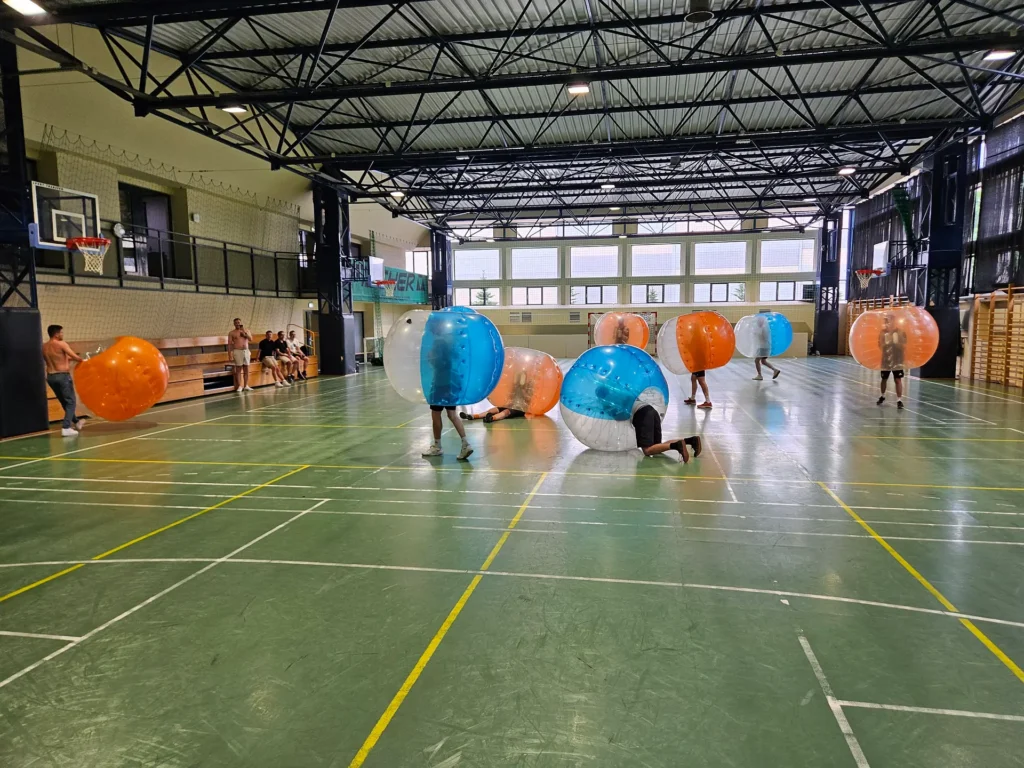 Teams in orange and blue bumper balls in a sports hall