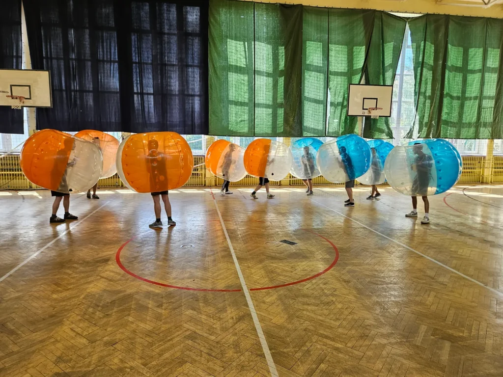Teams in orange and blue bumper balls in a sports hall