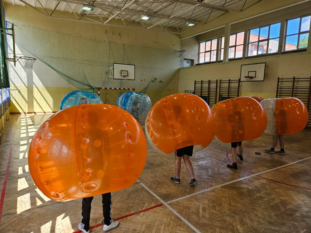 Teams in orange and blue bumper balls in a sports hall