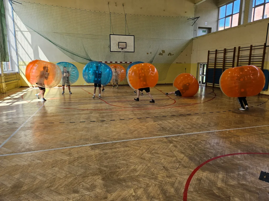 Teams in orange and blue bumper balls in a sports hall