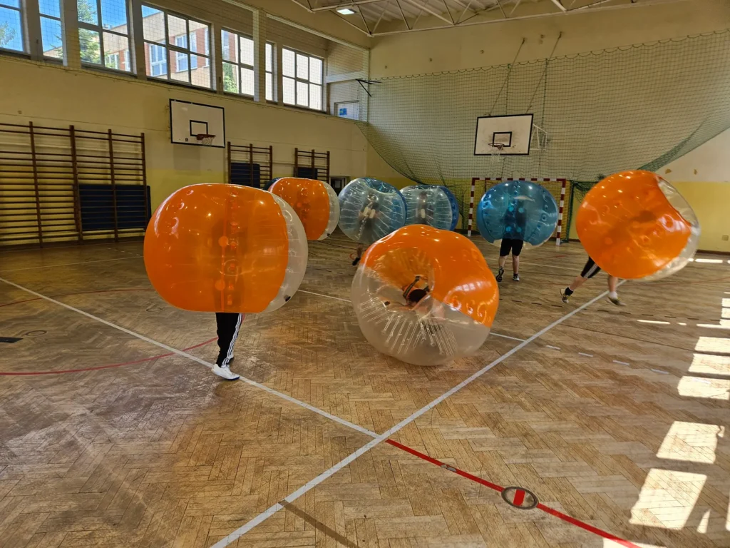 Teams in orange and blue bumper balls in a sports hall