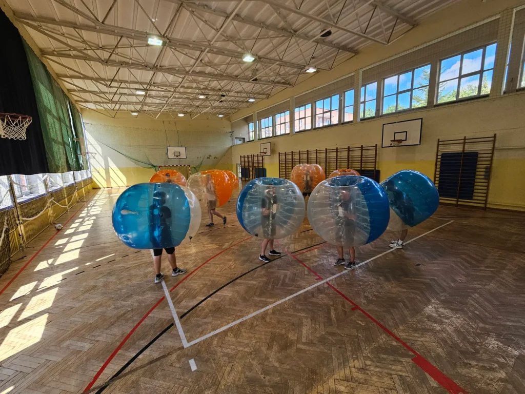 Teams in orange and blue bumper balls in a sports hall