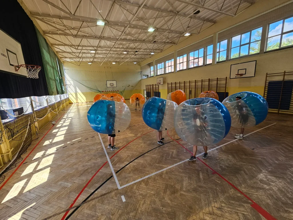 Teams in orange and blue bumper balls in a sports hall