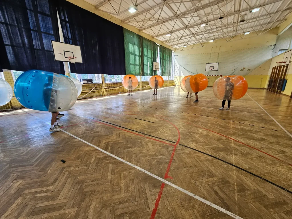 Teams in orange and blue bumper balls in a sports hall