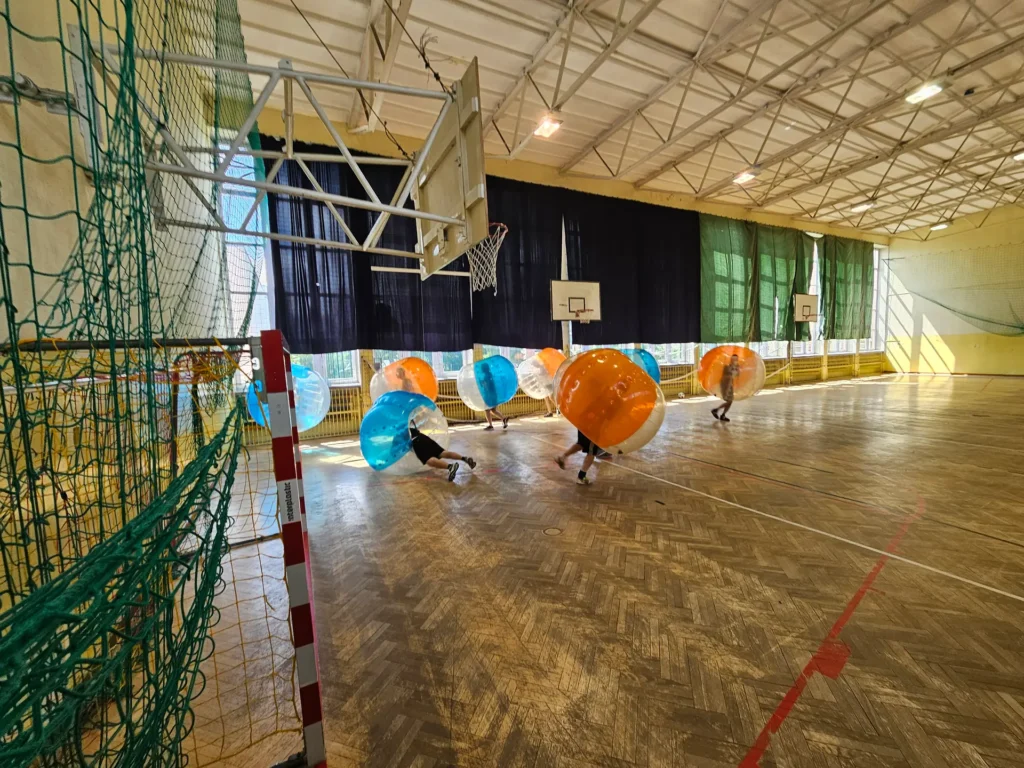 Teams in orange and blue bumper balls in a sports hall