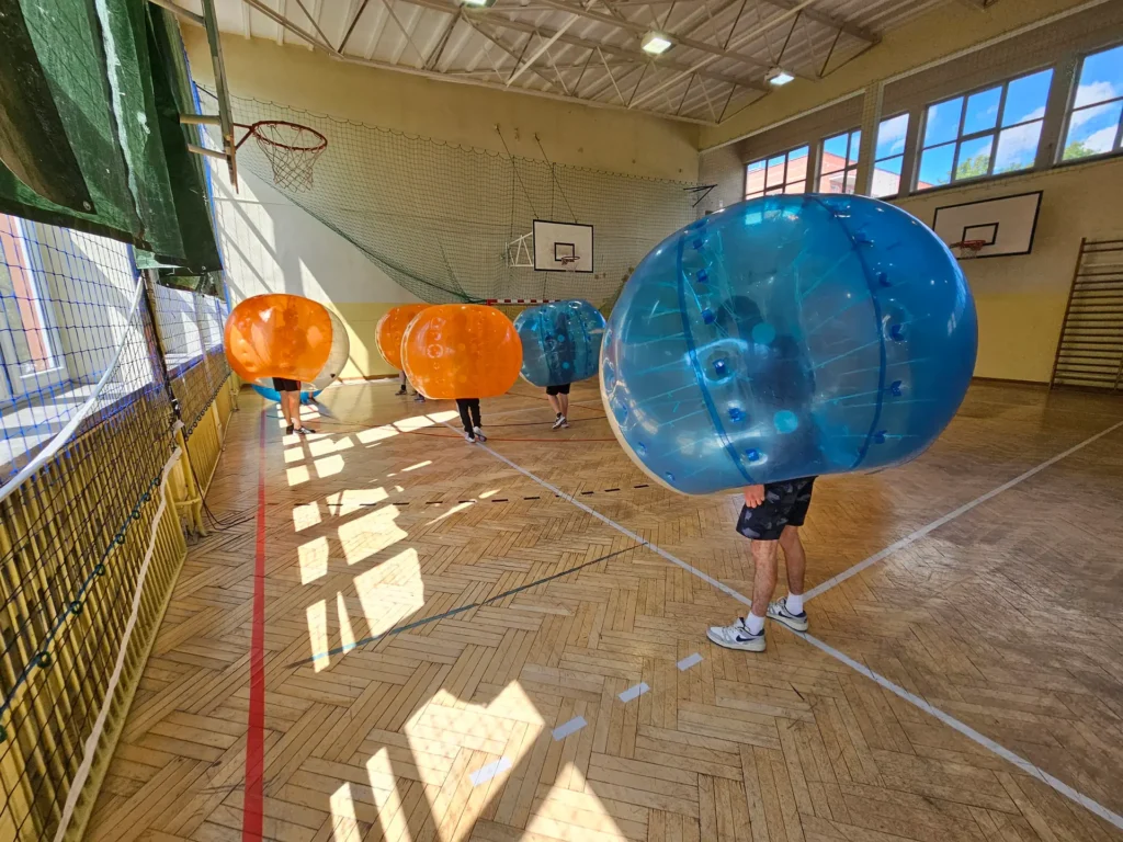 Teams in orange and blue bumper balls in a sports hall